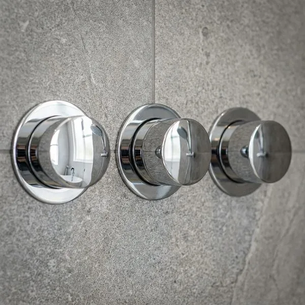 Triple-control concealed thermostatic shower valve in chrome on grey stone-effect tiling